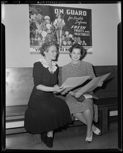 Two women in front of vegetable poster