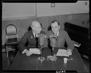 Two men seated behind W34B and WAAB microphones