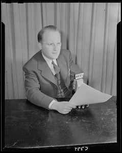 Man with glasses seated at WEEI microphone