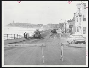 Sand and Gravel tossed up by the storm is cleared from Winthrop Shore Drive today by MDC men and equipment.
