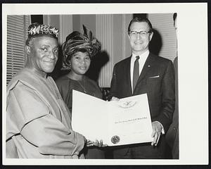 Ambassador from Revolt - Torn Country... Chief S.O. Adobo (L) Ambassador of Nigeria to the U.N., and Mrs. Adebo (C) receive a Paul Revere Scroll from Lt. Gov. Elliot Richardson of Mass., acting governor in absence of vacationing Gov. John Volpe, (1/18). Scroll entitles the ambassador among other things, to dump tea into Boston Harbor, coast down Beacon Hill (weather permitting), hang no more than two (2) lanterns in the belfry of the Old North Church, etc.