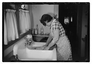 A woman doing laundry at a sink with a washboard