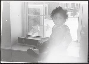 Young child sitting in windowsill