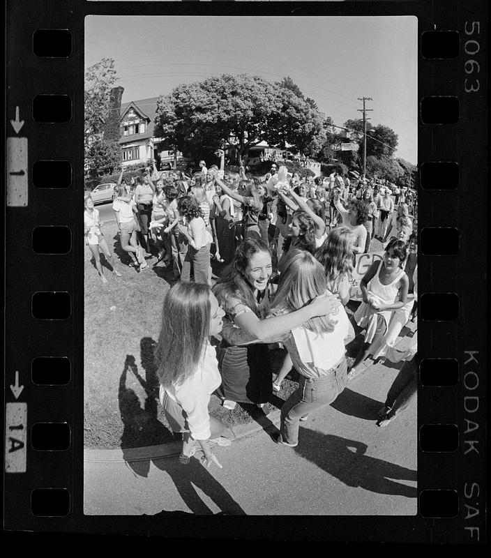 Two women hug while crowd cheers