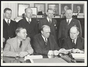The Dolan case nears its end. This photo was taken this noon after Atty. Eugene Clennon (standing at extreme right), representing the Massachusetts Bonding Company, passed to Mayor Mansfield checks covering "liabilities ... rising out of the acts of Edmund L. Dolan." Seated, left to right, are City Treasurer John H. Dorsey, Mayor Mansfield and City Collector John F. Doherty. Standing, Asst. Corp. Counsel Lewis H. Weinstein, Corporation Counsel Henry Foley, City Council President John I. Fitzgerald and Atty. Clennon.