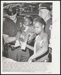 Picket in The Arms of the Law-- A small Negro child is gently carried by a New York City policeman as he removes her from road where she was sitting in front of a truck today. Another policeman leads an older girl away from site of construction work of Downstate Medical Center in Brooklyn, N.Y., where ten children were sitting in road. The father of five of the children, Willie Brinson, lead them into road as part of a demonstration against alleged bias on employment of Negroes and Puerto Ricans in construction traded.
