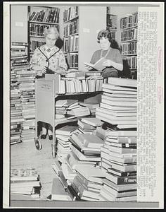 Librarians at San Francisco State College got an assist from more than 50 volunteers 1/19 in an effort to re-shelve thousands of books checked out by strikers and other dissidents at the trouble-plagued campus. The library is in a state of chaos as the result of daily "book-ins" by dissidents who check out huge numbers of books and immediately check them back in. In addition, thousands of books have been tossed on the floor, others have been moved to the wrong shelves and still more have been stolen. Here, Dr. Janet MacWilliams (L), asst. librarian, and Mrs. Harvey York, classify books for shelving.