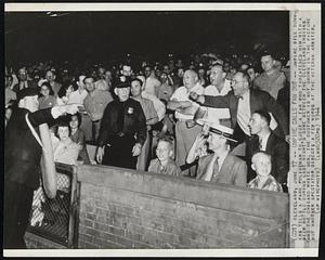 Umpire Calls Fan Out -- Umpire Bill Summers tells a park policeman to eject a fan who threatened him with a beer bottle during last night's game between The Cleveland Indians and The Chicago White Sox. The customer is not shown in the picture but another spectator directs a few words at the veteran arbiter.