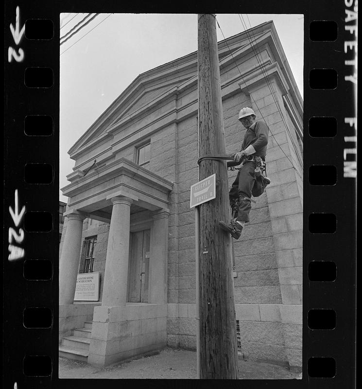 Man climbing pole near Customs House