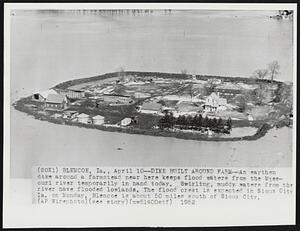 Dike Built Around Farm--An earthen dike around a farmstead near here koops flood waters from the Missouri river temporarily in hand today. Swirling, muddy waters from the river have flooded lowlands. The flood crest is expected in Sioux City Ia. on Monday. Blencoe is about 50 miles south of Sioux City.