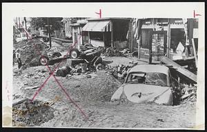 Debris and Dirt nearly cover car on a Scranton, Pa., street following flood. Owner today expressed hope of repairing it but the situation looks none too bright.