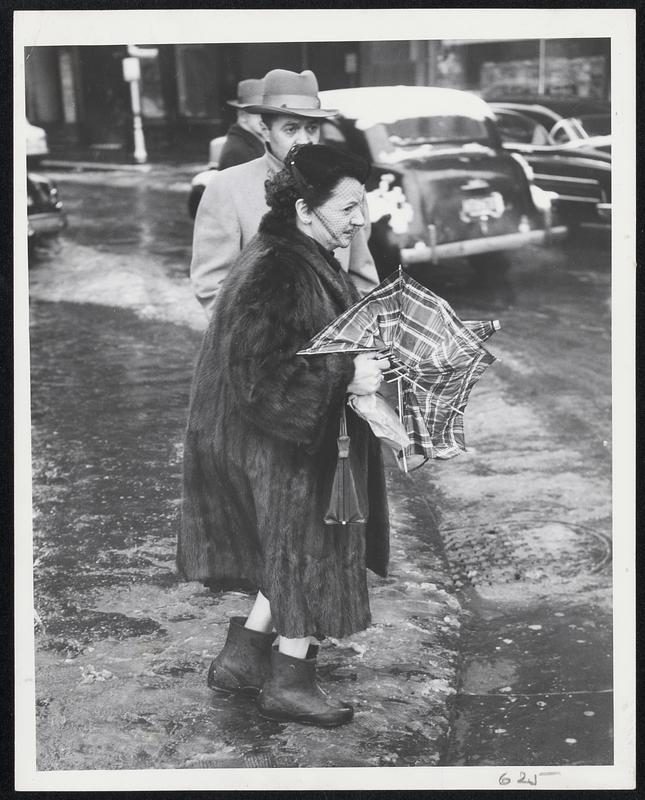 Sloshing Through Slush in yesterday's storm at Tremont and Boylston streets corner yesterday were these hardly feminine citizens. Left: a frustrated woman contemplates the cost of a new umbrella after her plaid job collapsed in the wind. Center: another lady grimaces after having been soused by a passing truck. Right: one little gal could even smile even though she wore no protection for her shoes.