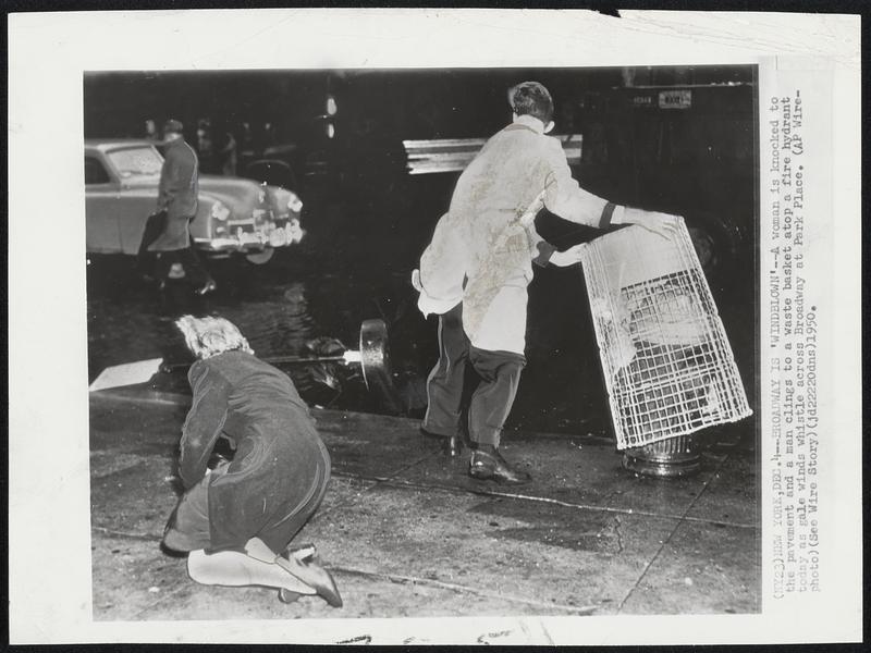 New York – Broadway Is ‘Windblown’ – A woman is knocked to the pavement and a man clings to a waste basket atop a fire hydrant today as gale winds whistle across Broadway at Park Place.