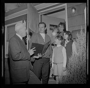 Norman Doyle showing a document to a family in their doorway