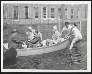 Mayor’s Flagship is propelled by two husky volunteers down what was Margin street, Hyde Park. With the mayor, in the stern, were, from left, Dr. John H. Cauley, health commissioner; reporter Dick Jacobson of the Traveler, and Fire Commissioner Francis X. Cotter. The Mayor promised every effort would be taken to keep damage at a minimum.