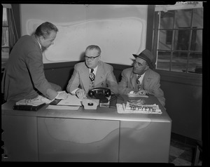 Three men seated at desk