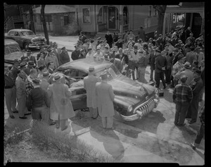 Group of people gathered around a vehicle in the street