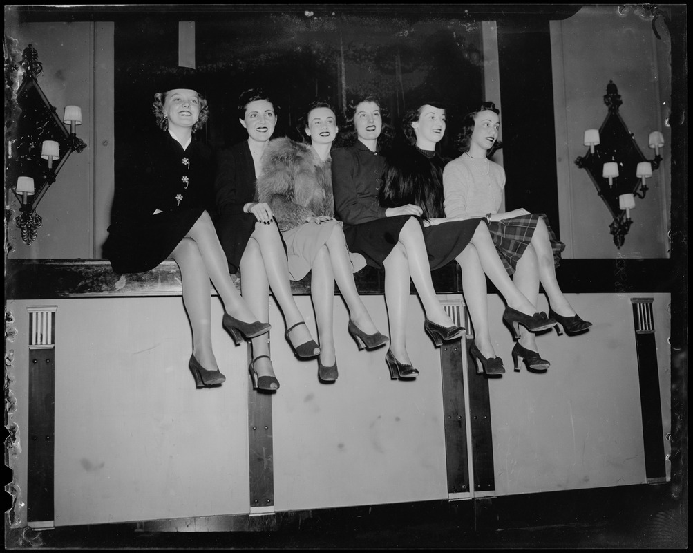 Skaters sitting on low wall, including Sonja Henie