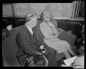 Sonja Henie on the couch, speaking with a man