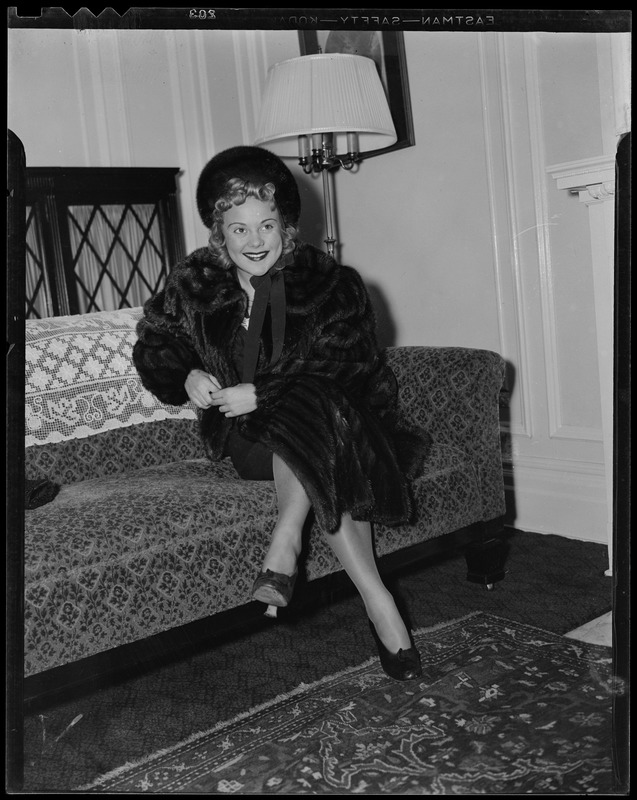 Sonja Henie on arrival seated on couch