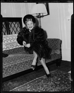 Sonja Henie on arrival seated on a couch