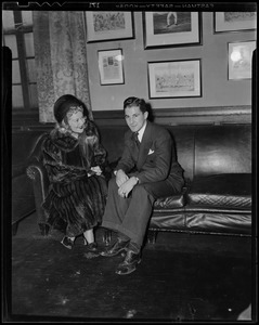 Sonja Henie on couch, talking with a man