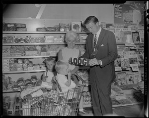 George C. Lodge holding up a Lodge sign to a young child in a shopping cart