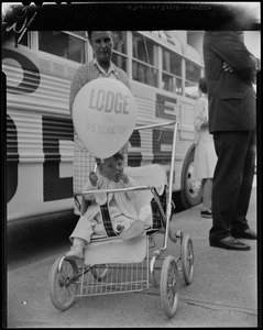 Young child in a stroller holding a Lodge for U.S. Senator balloon