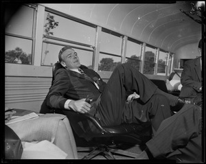 George C. Lodge lounging on a chair in a bus