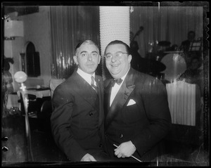 Eddie Cantor poses with another man while the band plays in the background