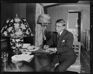 Eddie Cantor seated at desk and writing something, possibly a check