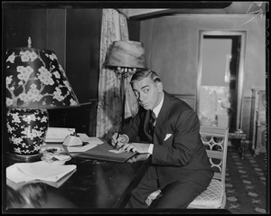 Eddie Cantor seated at desk and writing something, possibly a check