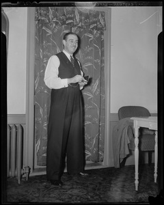 Morton Downey standing in a room, holding a cigarette case