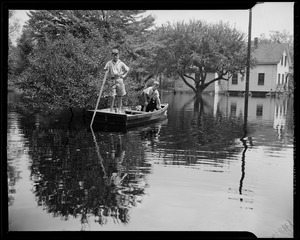 Two children in boat with dog, wading through waters