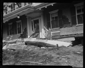 Two boys waving from their home amid debris