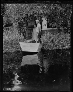 A young man and woman look out to the flood waters from doorway