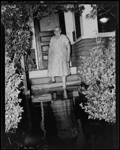 Woman walking off her front porch steps to the flood water