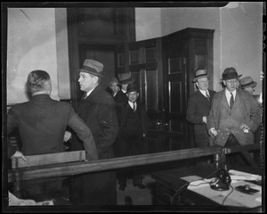 Men gathered inside of a room wearing coats, one of which is Councilman Robert Gardiner Wilson