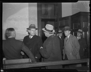 Men gathered inside of a room wearing coats, one of which is Councilman Robert Gardiner Wilson