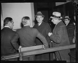 Men gathered inside of a room wearing coats, one of which is Councilman Robert Gardiner Wilson