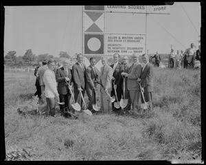 Smaller group of men, all with shovels, in front of "The Site of New England Shopping Center" sign
