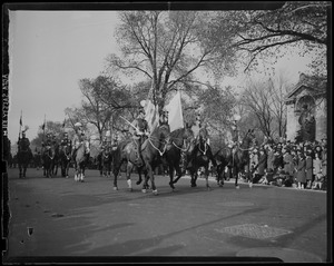 Mounted troops with flags marching down the street during the Armistice Day Parade
