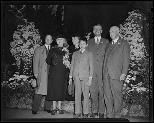 Governor Elect Leverett Saltonstall, son Billy, and Mrs. Leverett Saltonstall standing with others at Autumn Flower Show in Horticultural Hall