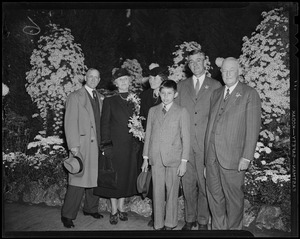 Governor Elect Leverett Saltonstall, son Billy, and Mrs. Leverett Saltonstall standing with others at Autumn Flower Show in Horticultural Hall