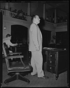 Man standing at desk and addressing someone off camera