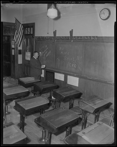 John Kane, Assistant Custodian of Public Schools for Roxbury Area, views message on blackboard at fire-ruined Hyde School