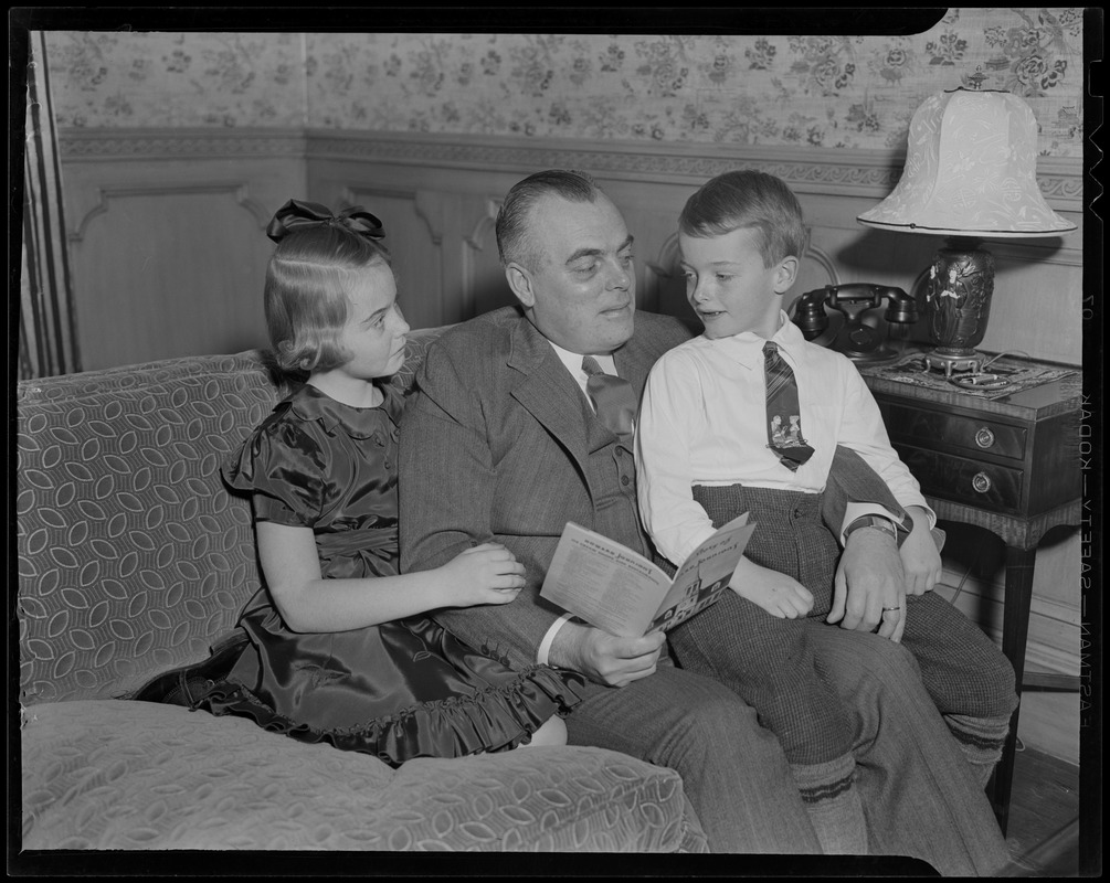 Howard Johnson reading to two children on the couch