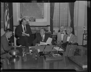 Governor Dever with four other men in his office, reviewing documents