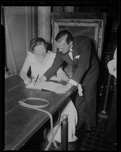 Princess Juliana looks on as Prince Bernhard signs a book