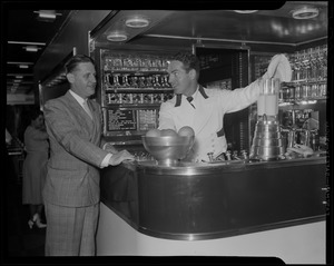 Fred Waring demonstrating a mixer as another man looks on